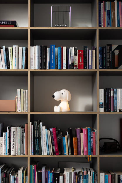Snoopy First Light lamp placed beside a Peanuts comic book collection