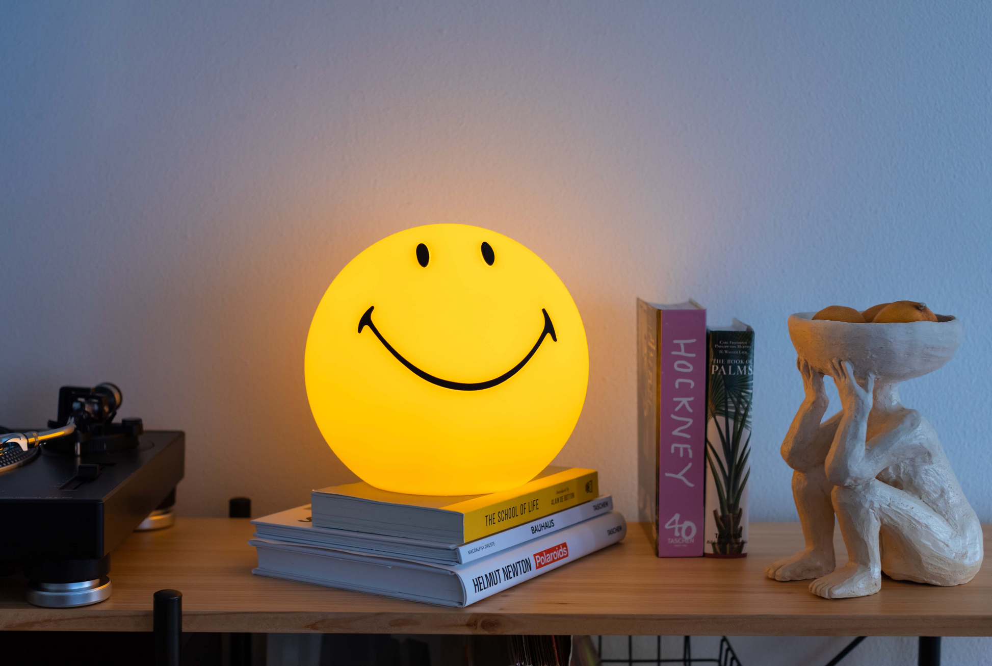 Smiley face lamp on books with a decorative figure and books in the background
